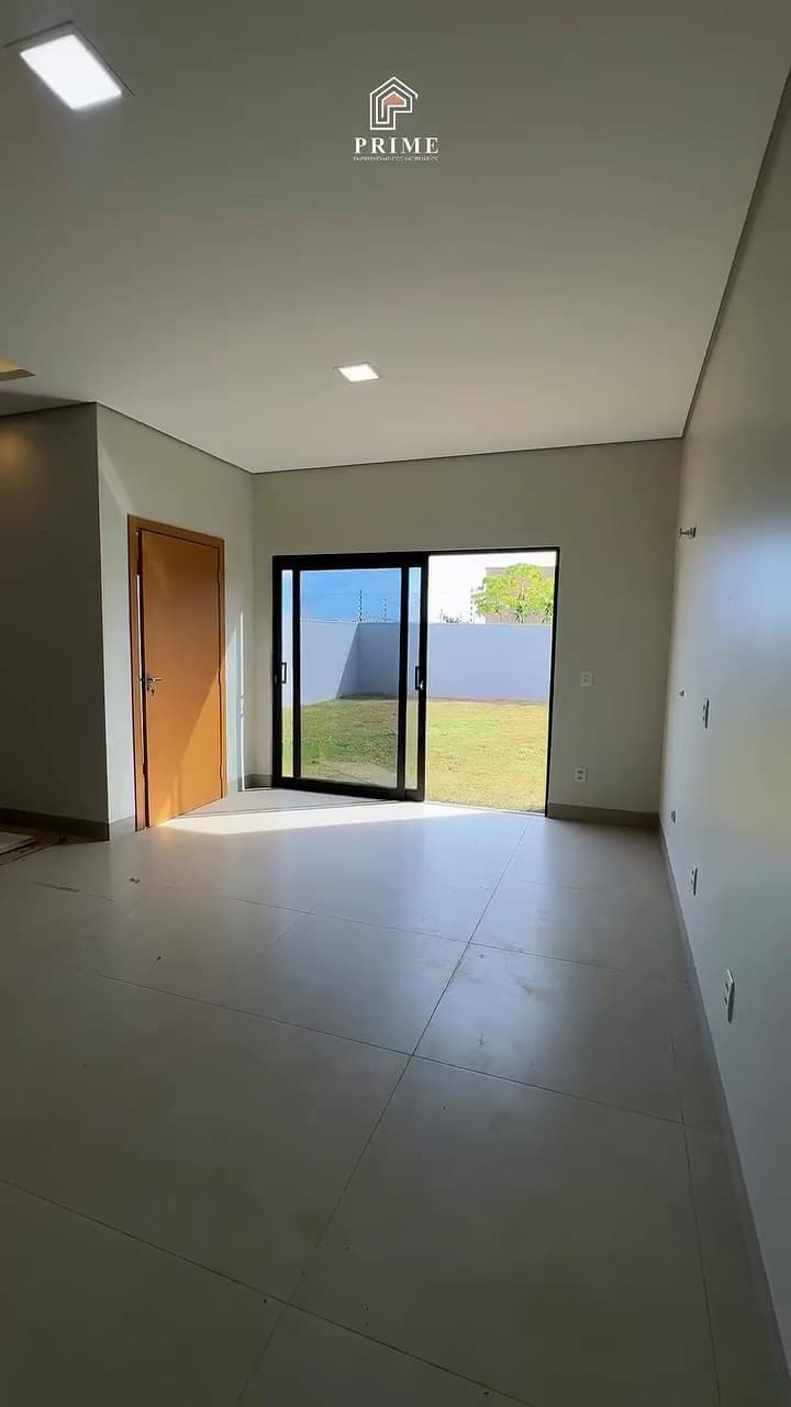 Sala com esquadria de vidro abrindo para o quintal gramado