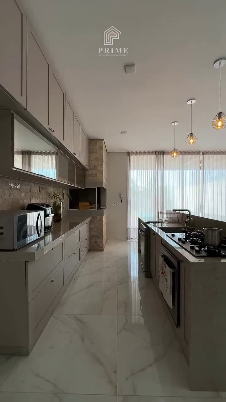 Cozinha planejada com bancada em pedra, cooktop e revestimento em travertino